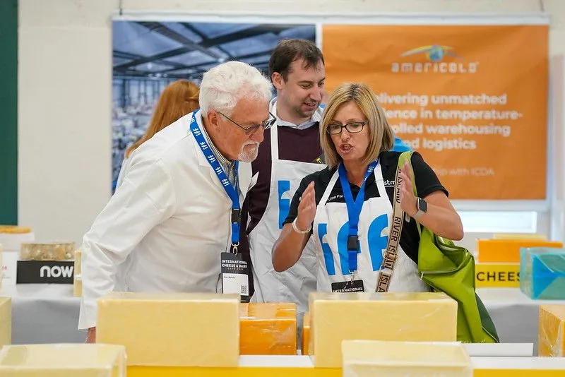 Judges in aprons inspecting blocks of cheese at an awards event