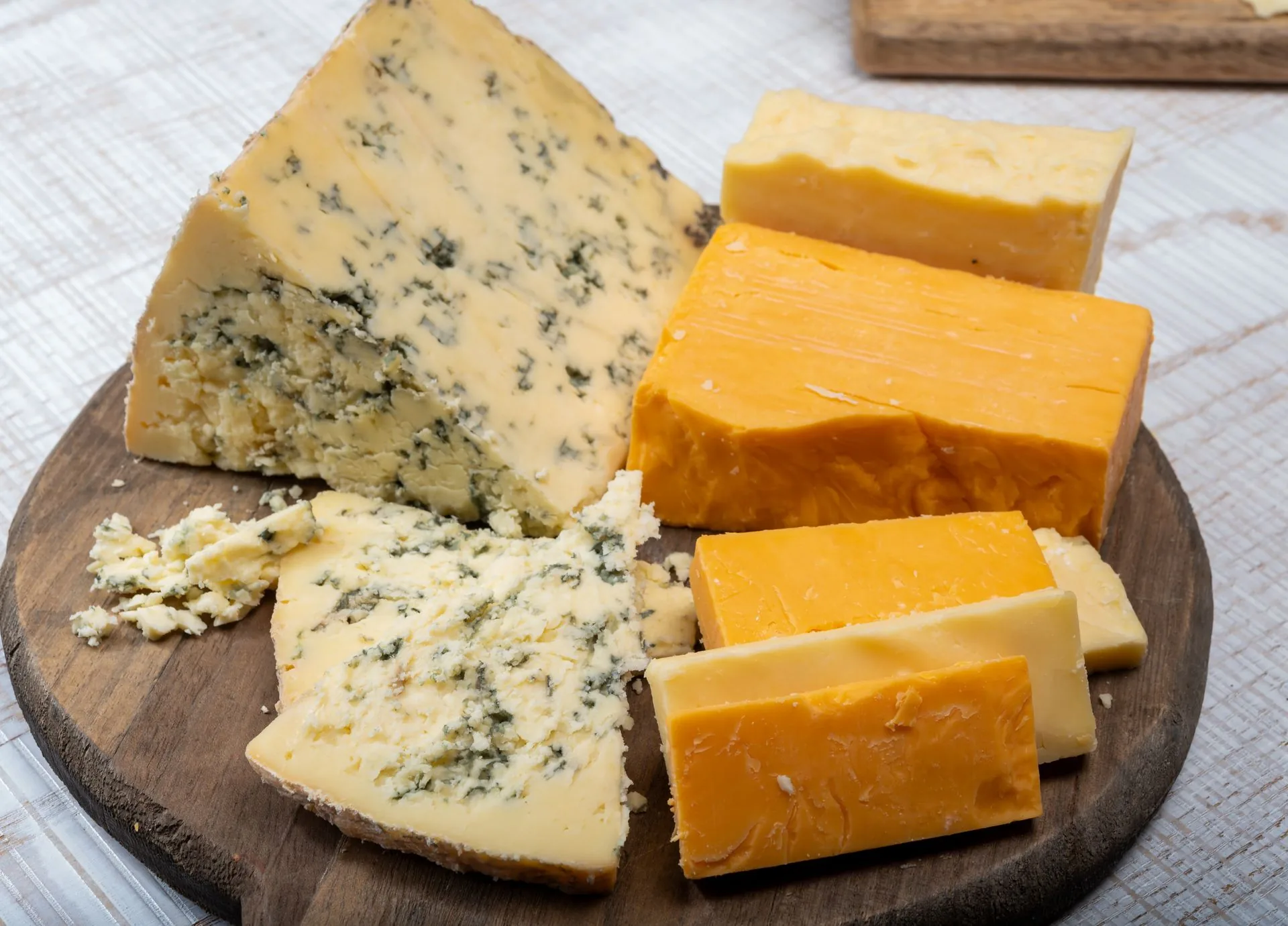 Wedges of blue-veined and orange cheddar cheese on a wooden board