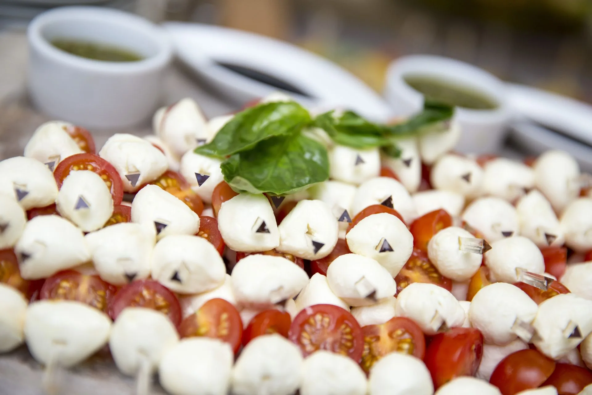 Skewers of mozzarella pearls and cherry tomatoes topped with fresh basil