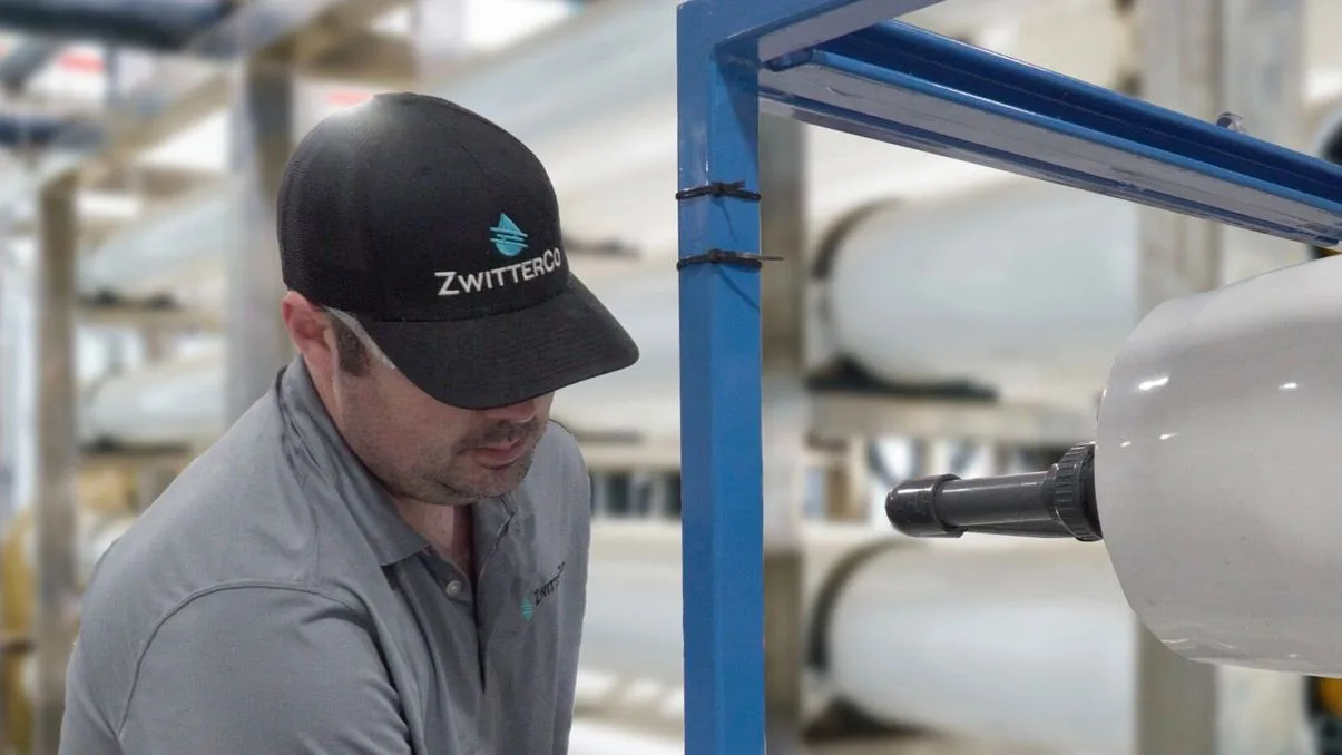 Worker in a ZwitterCo cap inspecting reverse osmosis membrane filtration equipment