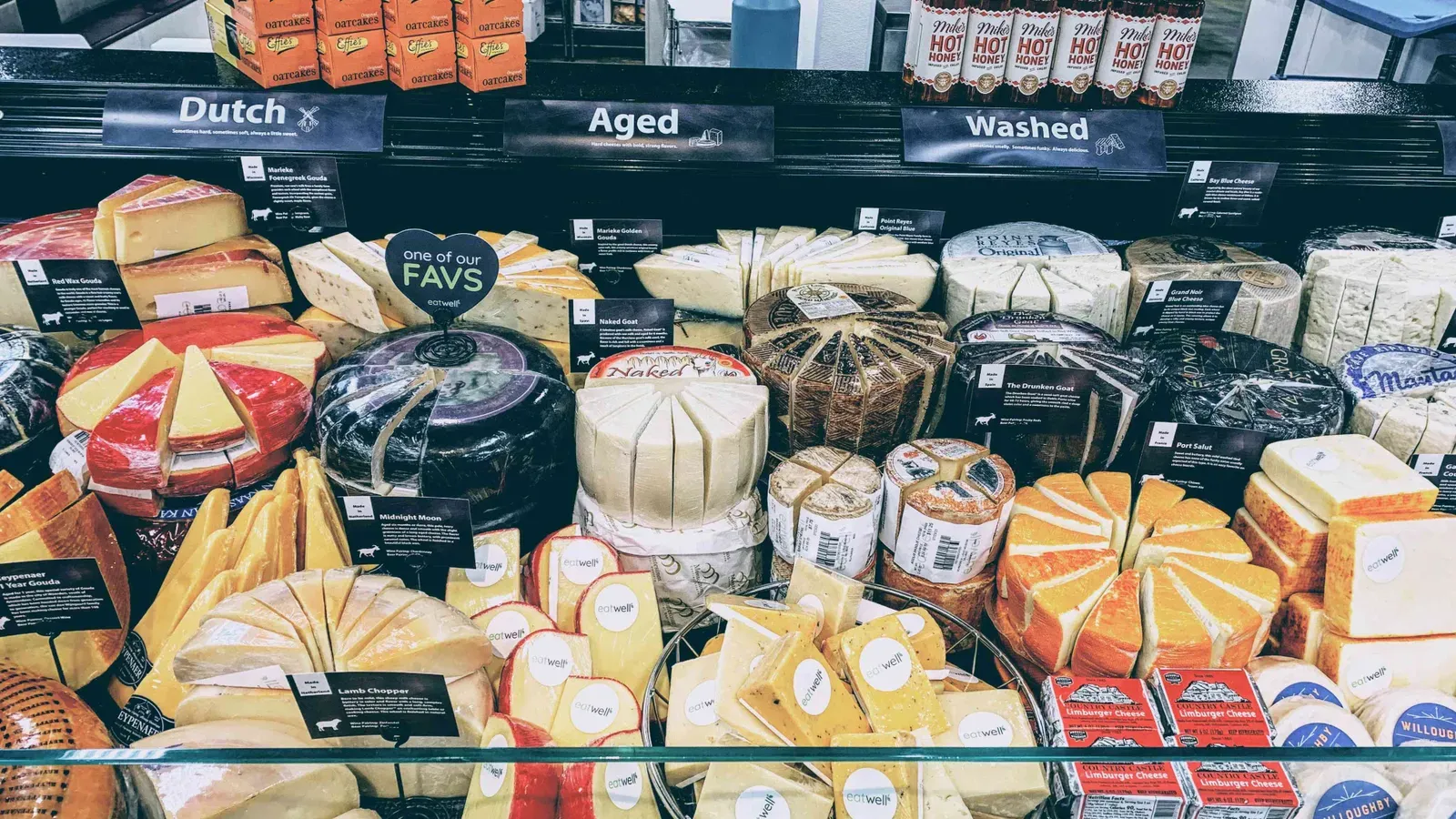 Stocked cheese counter with Dutch, Aged and Washed section signs