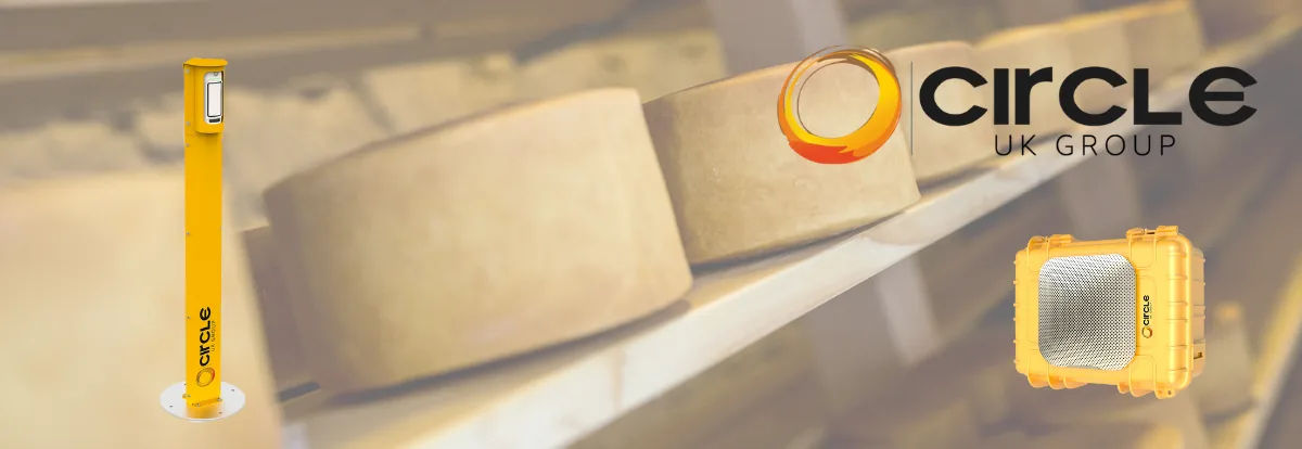 Cheese wheels on a conveyor behind Circle UK Group safety bollard and equipment product shots