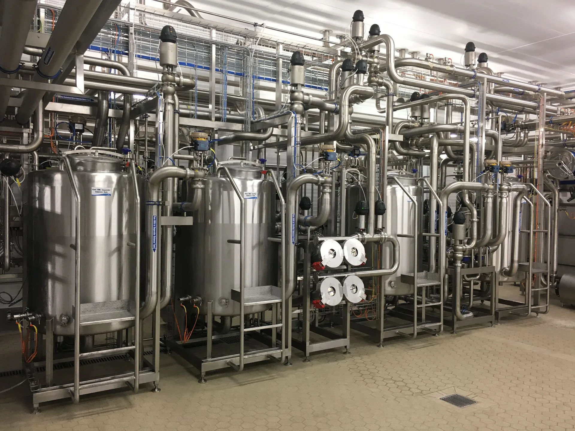 Stainless steel balance tanks and pipework inside a dairy processing plant