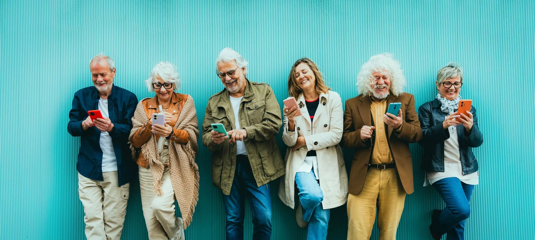 A group of older friends laughing together over their smartphones