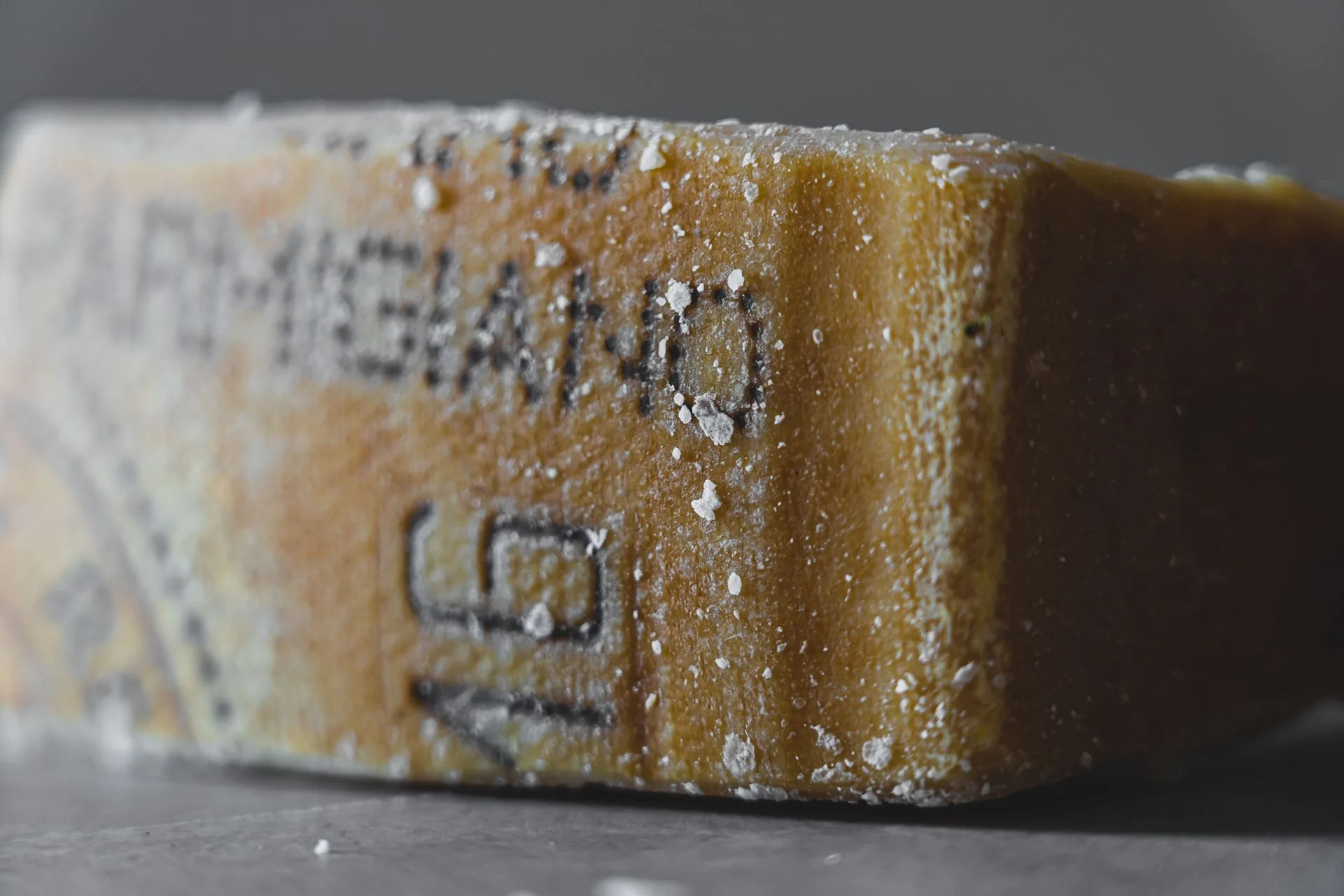Close-up of a Parmigiano cheese wedge showing the stencilled rind markings