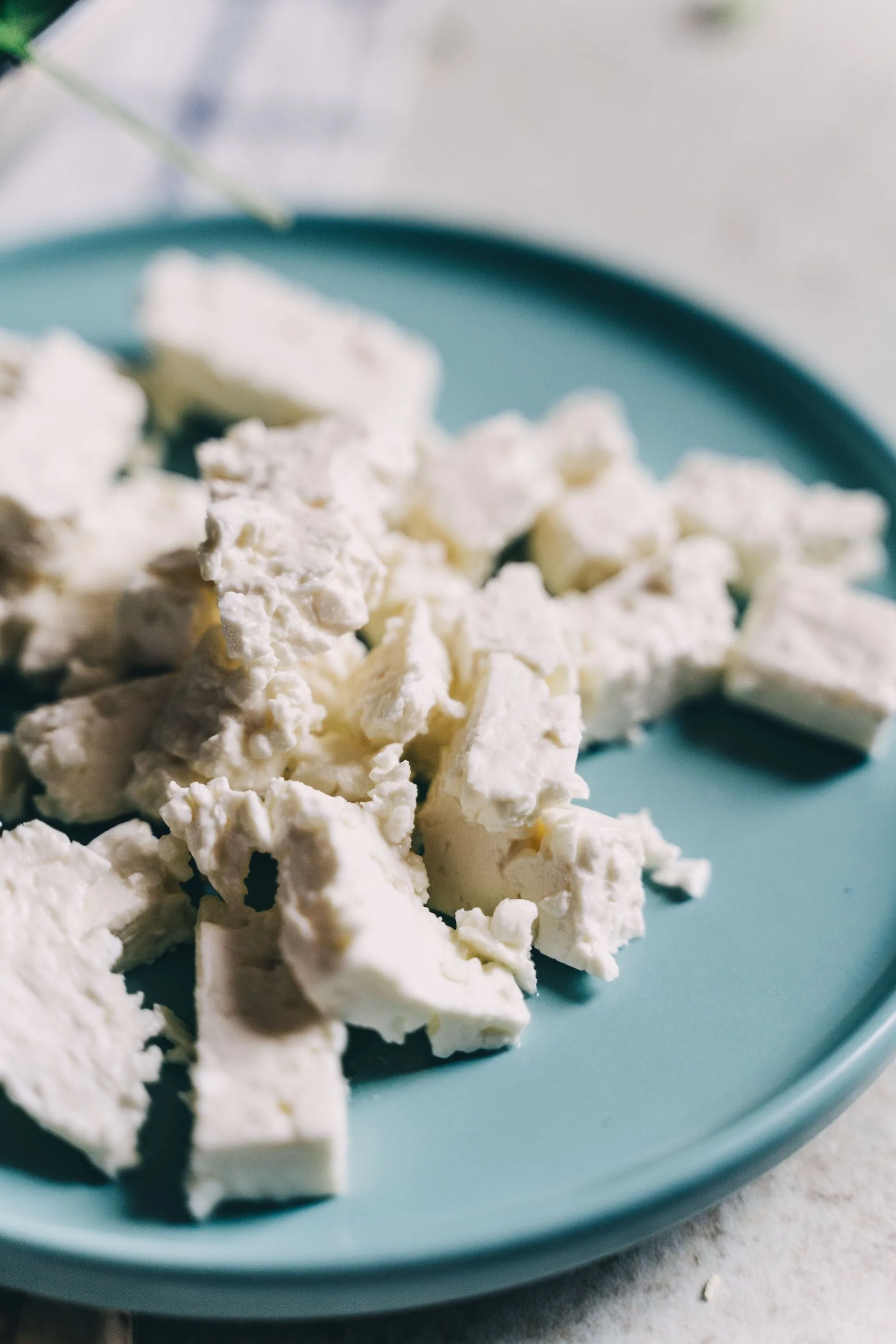 Chunks of crumbled white feta cheese on a blue-grey plate