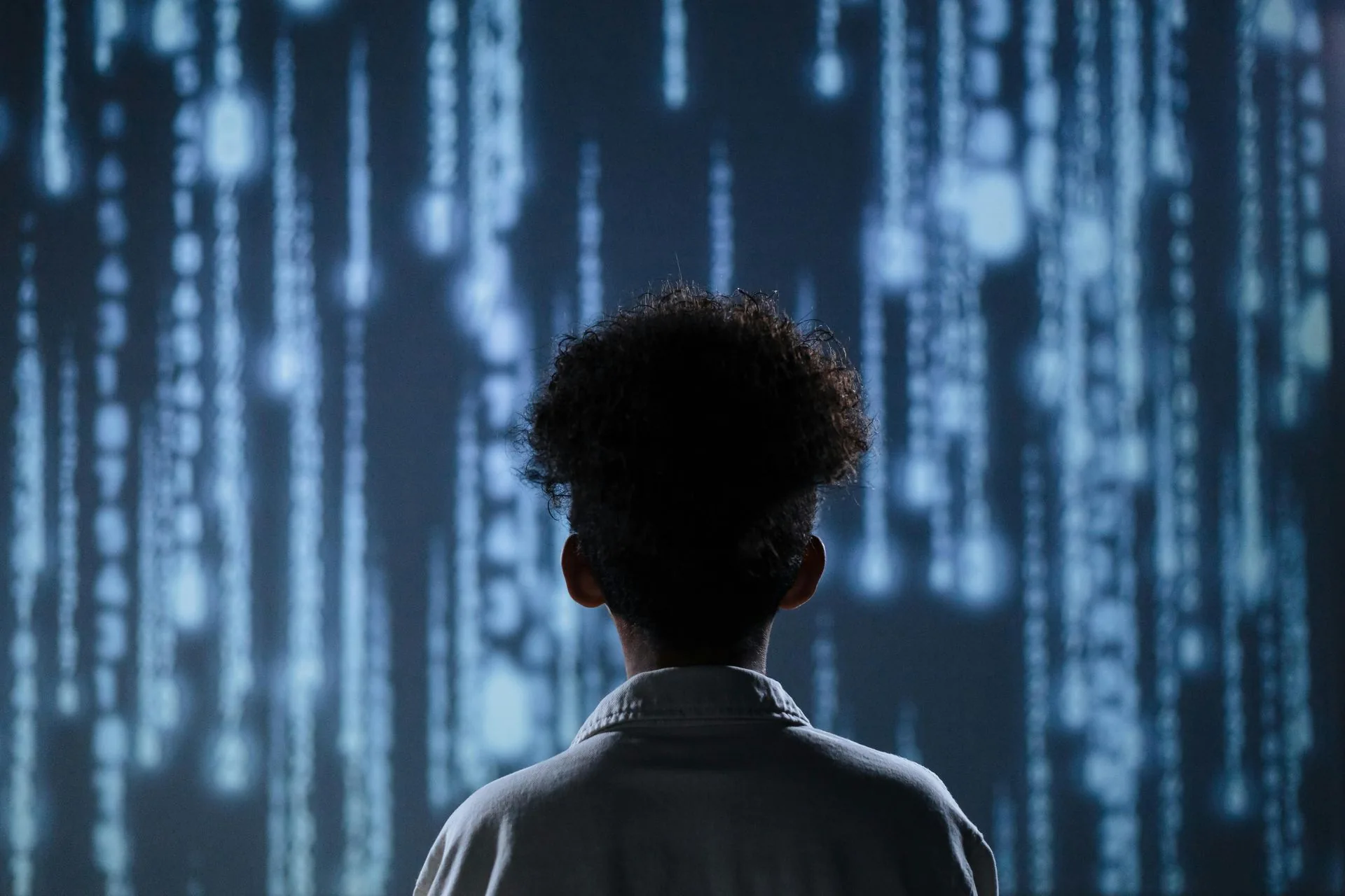 Silhouetted person facing a wall of falling blue digital code