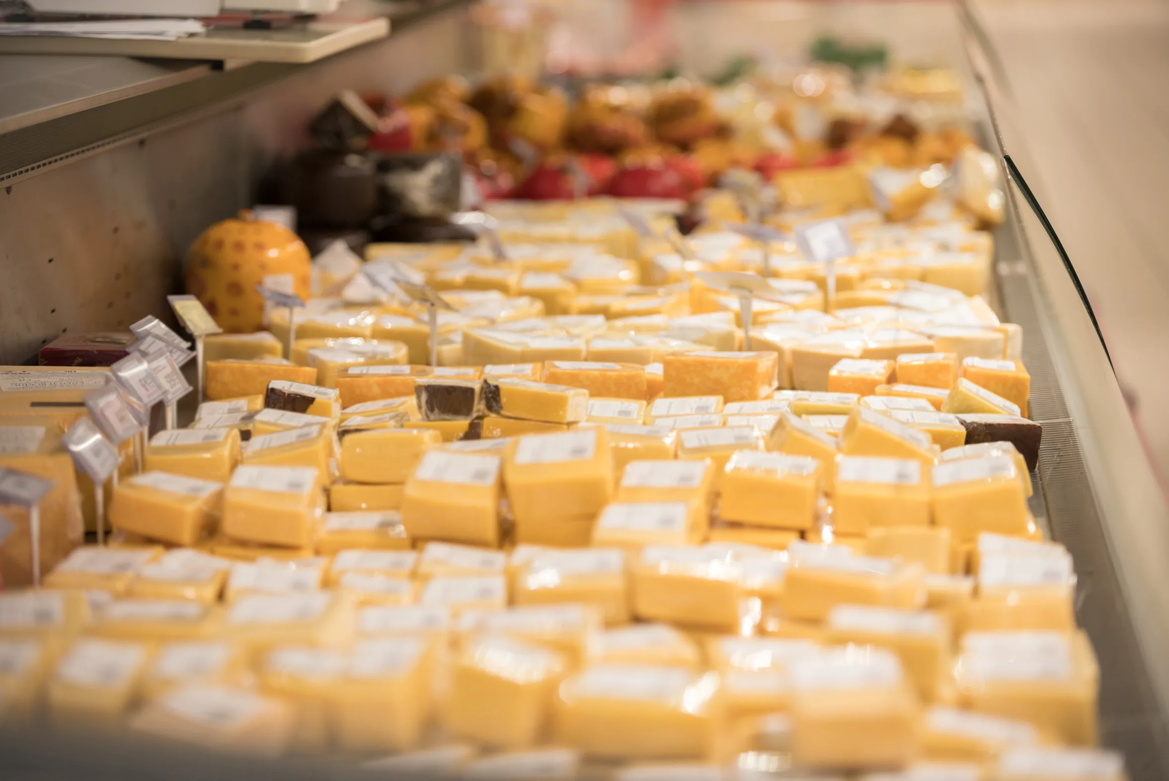 A supermarket cheese chiller packed with vacuum-wrapped blocks of Cheddar and other hard cheeses